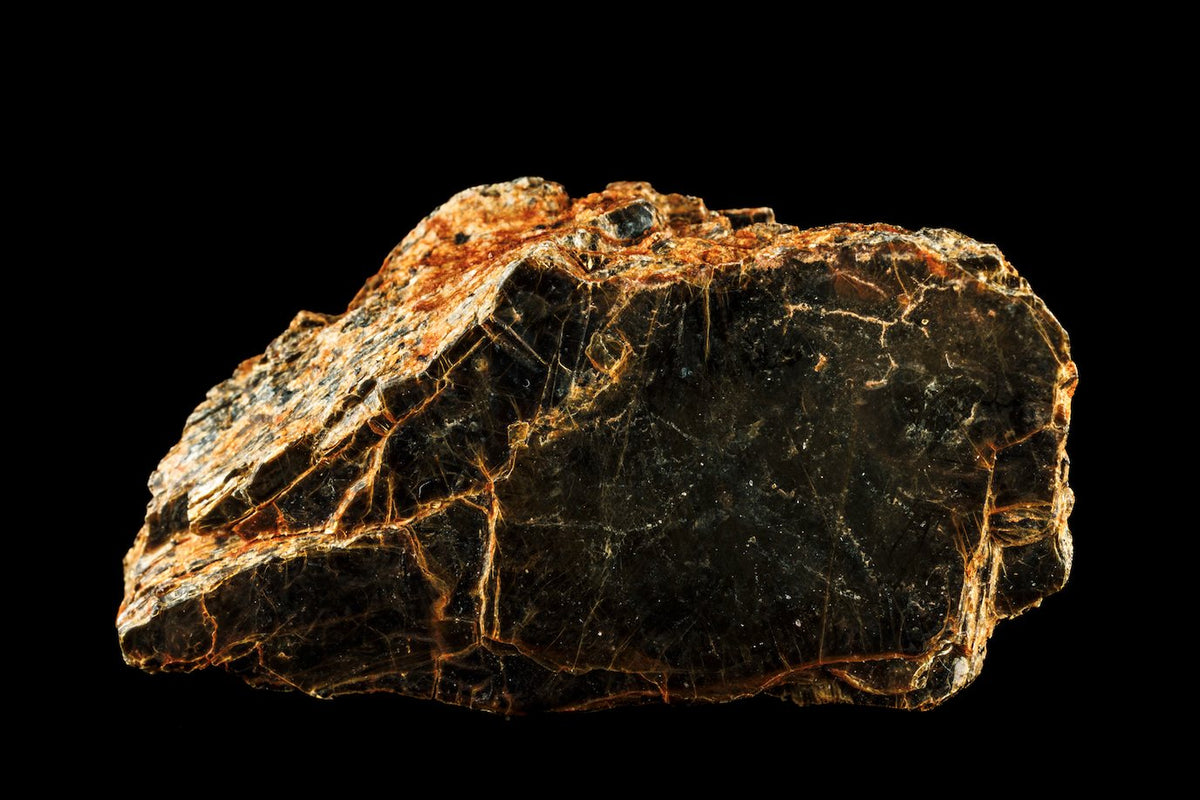 A specimen of volcanic biotite, black mica shot through with rust-coloured veins, on a black ground.